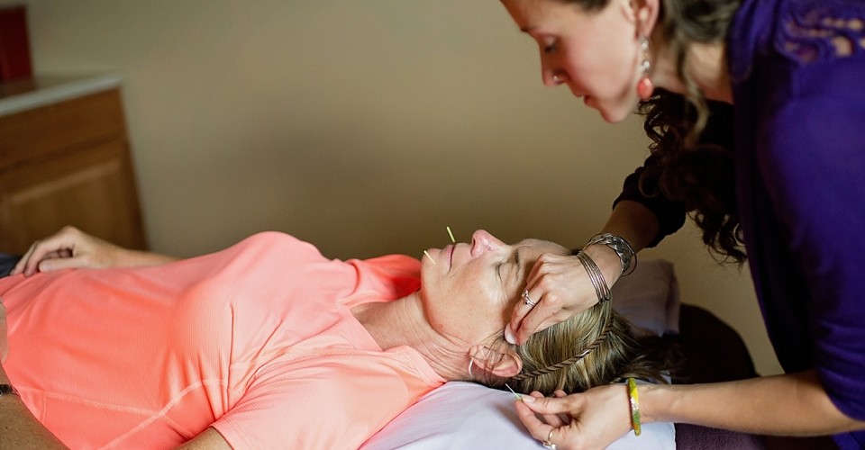 A woman receiving a gentle head massage from a therapist.