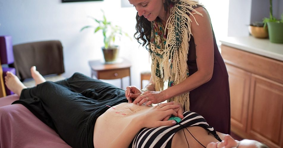 A woman receiving acupuncture treatment while lying down.