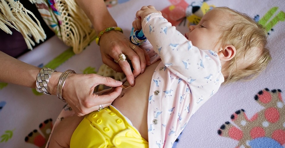 A toddler lies down while an adult applies a temporary tattoo.