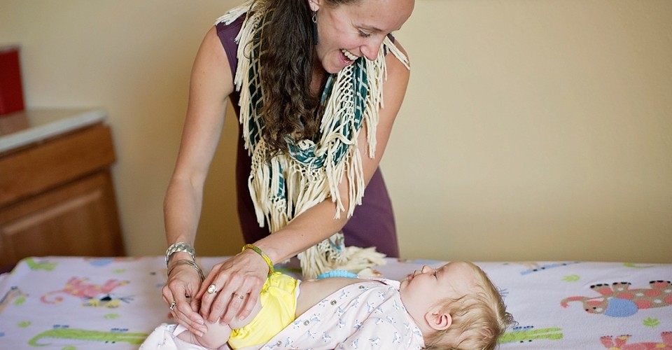 A joyful mother playing with her baby on a bed.