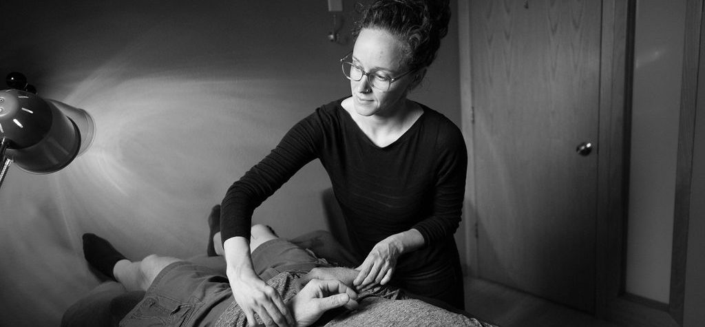 A woman giving a head massage to another woman lying down.