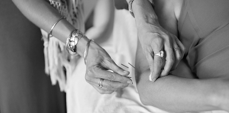 Close-up of hands with rings and bracelets gently touching skin.