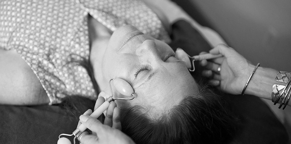 A person receiving a facial treatment with closed eyes.